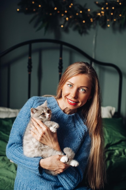 Una mujer con un gato se abraza en casa.