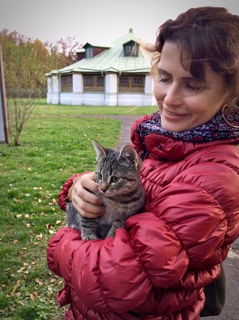 Foto mujer con gato de pie en el campo