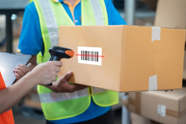 Mujer gerente profesional sonriendo del trabajador de logística del almacén verificación de trabajo escaneo de código de barras en la caja del paquete en el negocio de logística de la fábrica de distribución