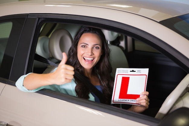 Foto mujer gesticulando pulgares arriba con un cartel de conductor principiante