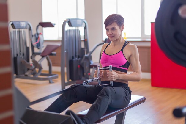 Mujer en el gimnasio haciendo entrenamiento de fuerza en el simulador