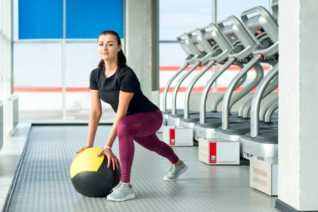 Mujer en el gimnasio relajante con balón medicinal