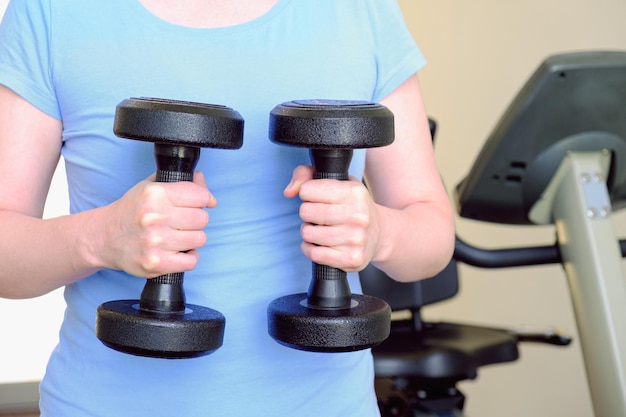 Mujer en el gimnasio sostiene pesas de metal Equipo deportivo para aumentar la masa muscular