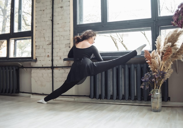 Mujer gimnasta o bailarina entrenando pierna estirándose por la ventana interior