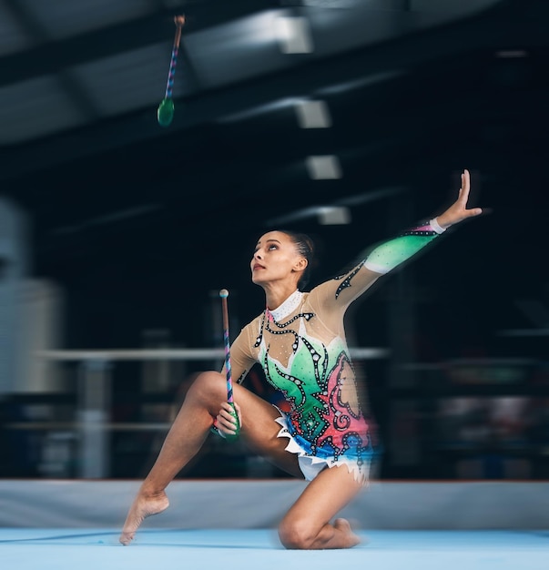 Foto mujer gimnasta y palos de baile con equilibrio y enfoque en un gimnasio para el arte de la danza entrenamiento de ejercicios y competencia deportiva de un atleta con movimiento para el espectáculo de fitness y deporte de bailarina