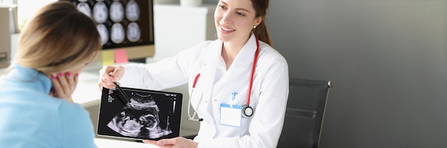 Mujer ginecólogo obstetra que muestra la fotografía del paciente del examen de ultrasonido del feto en la ...