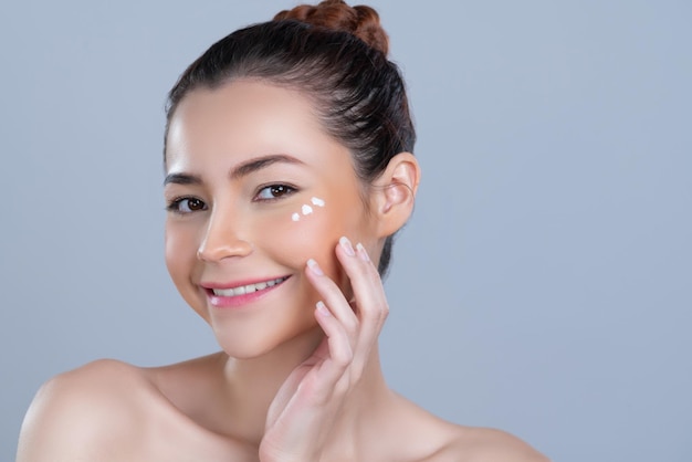 Mujer glamorosa de primer plano aplicando crema humectante en la cara para una piel perfecta