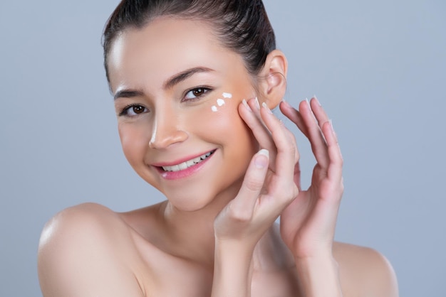 Mujer glamorosa de primer plano aplicando crema humectante en la cara para una piel perfecta