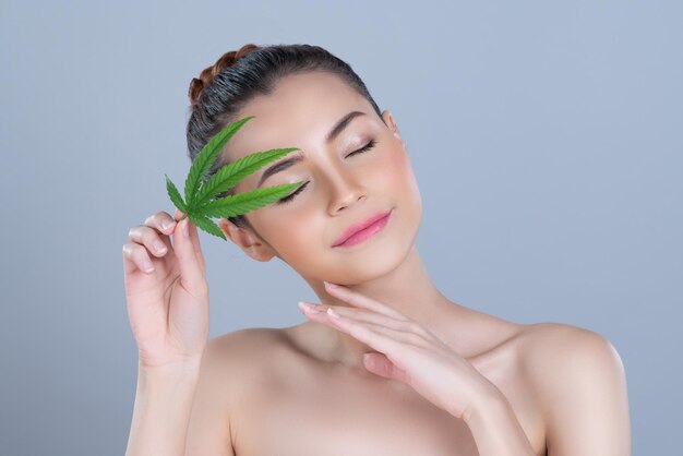 Mujer glamorosa de primer plano sostiene hoja verde como concepto de belleza de cannabis