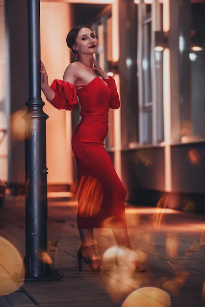 Una mujer glamorosa con un vestido rojo posando en la ciudad.