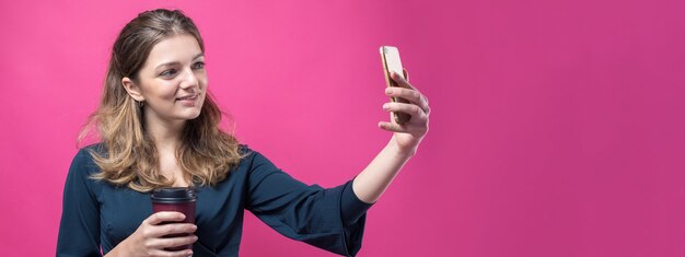 Mujer de glamour con una copa de café sobre un fondo rosa