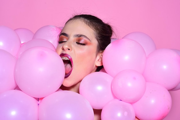 Mujer con globo sobre fondo de pared rosa