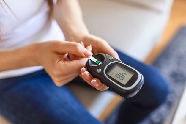 Mujer con glucómetro comprobando el nivel de azúcar en sangre en casa. Diabetes, concepto de salud