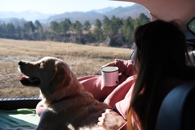 mujer con golden retriever mira las montañas