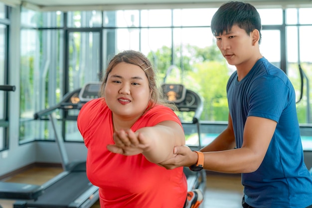 Una mujer gorda asiática entrena con su entrenador para hacer ejercicio y hacer dieta en el club del gimnasio