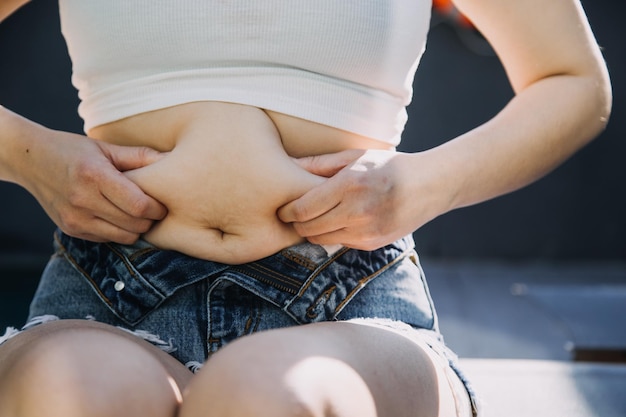 Foto mujer gorda, barriga gorda, gordo, obesa, mujer con la mano sosteniendo la grasa abdominal excesiva con cinta métrica, mujer, concepto de estilo de vida de dieta