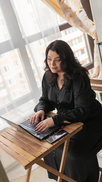 Mujer gorda computadora portátil niña negro africano hogar interior de trabajo moderno