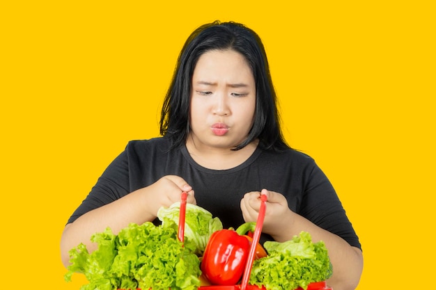 Mujer gorda dudosa mira verduras en el estudio