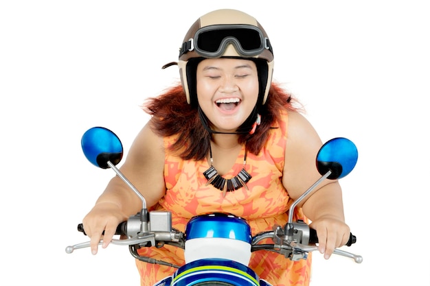 Mujer gorda feliz montando una motocicleta en el estudio