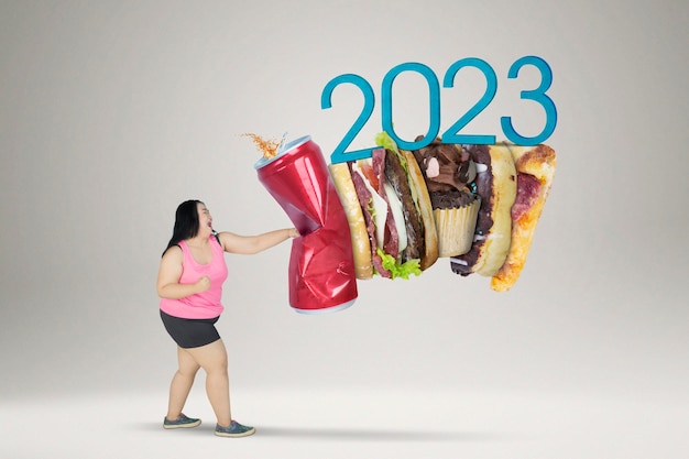 Mujer gorda golpea comida chatarra con números de 2023