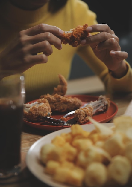 Mujer gorda muerde un trozo de pizza. La mujer con sobrepeso está comiendo comida rápida. La niña asiática tiene hambre.