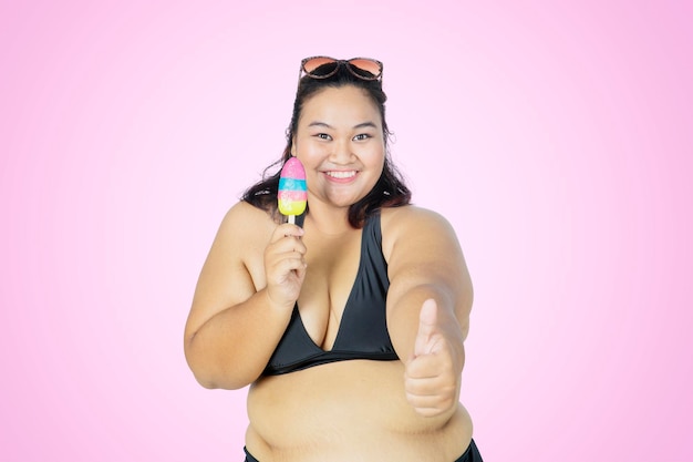 Mujer gorda muestra el pulgar hacia arriba mientras sostiene un helado