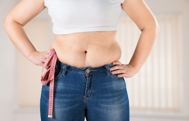 Mujer gorda y con sobrepeso midiendo su estómago