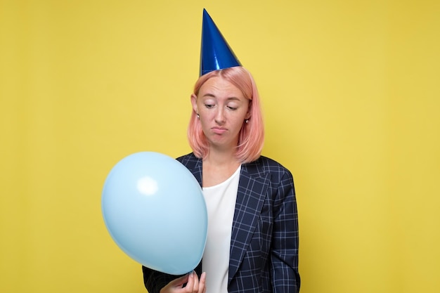 Mujer con gorra de cumpleaños con matraca Chica no quiere celebrar su cumpleaños