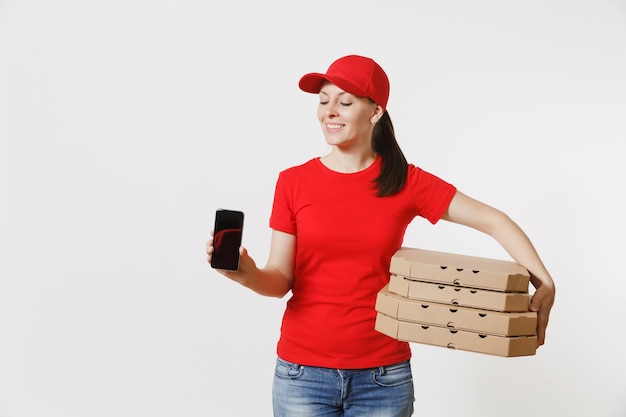 Mujer con gorra roja, camiseta dando orden de comida pizza italiana en cajas de cartón flatbox aisladas sobre fondo blanco. Mensajero femenino que sostiene el teléfono móvil con la pantalla vacía negra en blanco. Concepto de entrega.