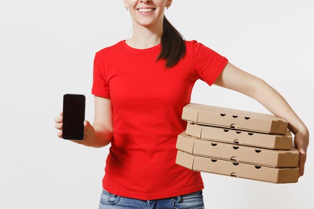 Mujer con gorra roja, camiseta dando orden de comida pizza italiana en cajas de cartón flatbox aisladas sobre fondo blanco. Mensajero femenino que sostiene el teléfono móvil con la pantalla vacía negra en blanco. Concepto de entrega.