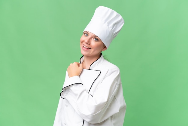 Una mujer con gorro de chef se para frente a una pantalla verde.