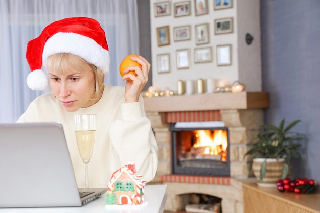 Una mujer con un gorro de Papá Noel felicita a familiares y amigos en una computadora portátil con Navidad Año Nuevo