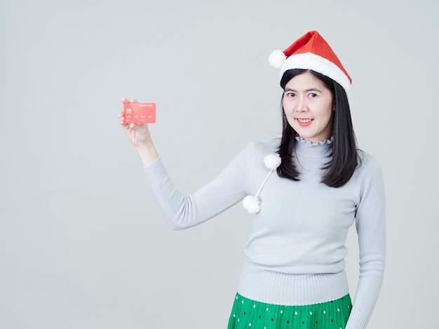 Mujer con gorro de Papá Noel en la mano mostrando tarjetas de crédito de compras