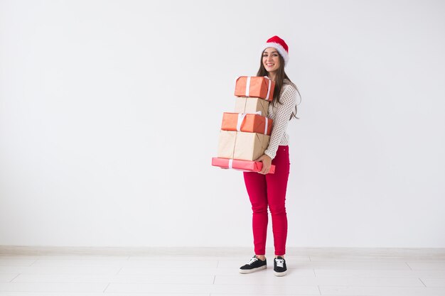 - Mujer con gorro de Papá Noel con muchos regalos sobre fondo blanco con espacio de copia