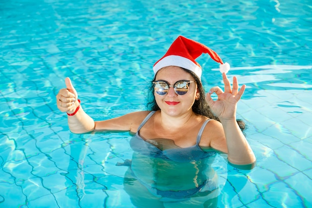 Una mujer con un gorro de Papá Noel en la piscina en la Navidad