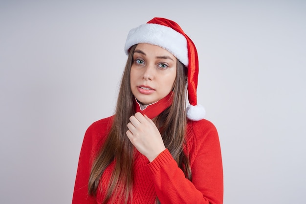 Mujer con gorro de Papá Noel, suéter rojo, asfixia quita una máscara protectora