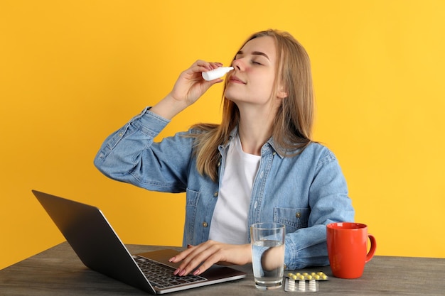 Mujer con gotas nasales sentado en el lugar de trabajo, concepto de secreción nasal