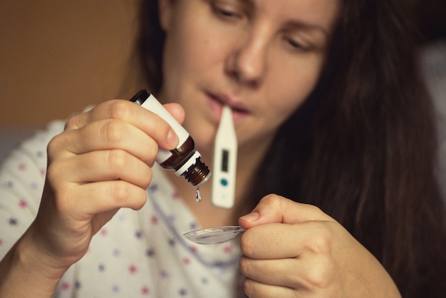 Mujer goteando medicina curativa en una cuchara