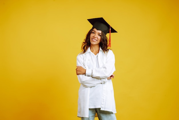 Mujer graduada con un sombrero de graduación en la cabeza posando en amarillo