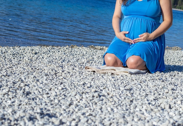 mujer gran embarazo avanzado caminando junto al lago en la playa de guijarros.tercer último trimestre femenino