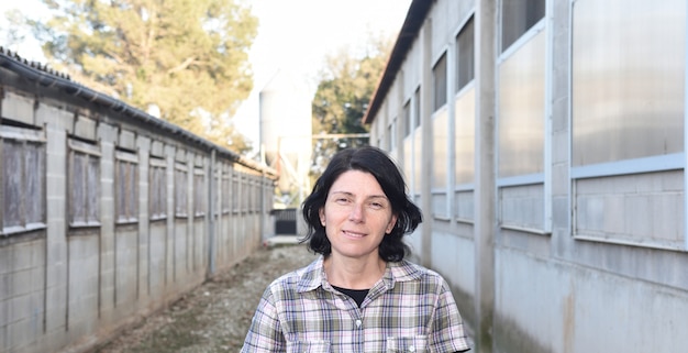 Mujer de granja frente a una granja de animales