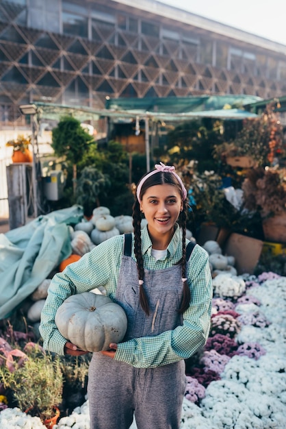 Mujer granjera feliz en un mono de mezclilla sostiene calabaza madura