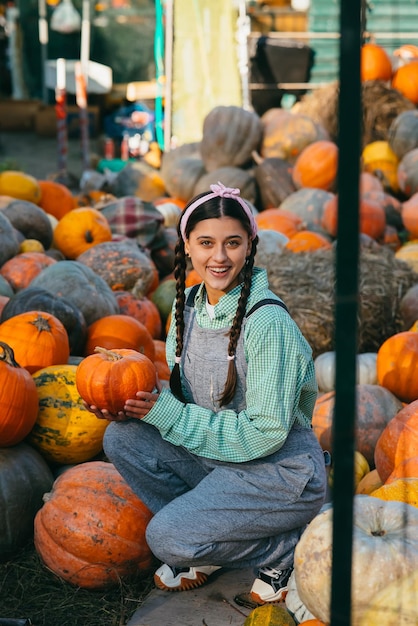 Mujer granjera en un mono de mezclilla elige calabaza madura