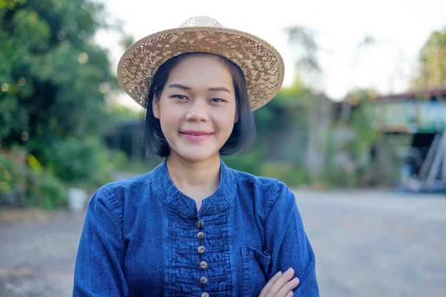 La mujer del granjero asiático usa la sonrisa del traje tradicional y cruza las manos en la granja