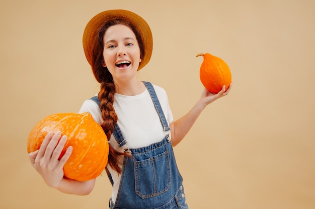 Mujer de granjero feliz disfruta de verduras orgánicas de calabazas maduras sobre un fondo beige