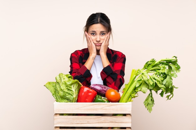 Mujer del granjero que sostiene verduras frescas en una cesta de madera infeliz y frustrado