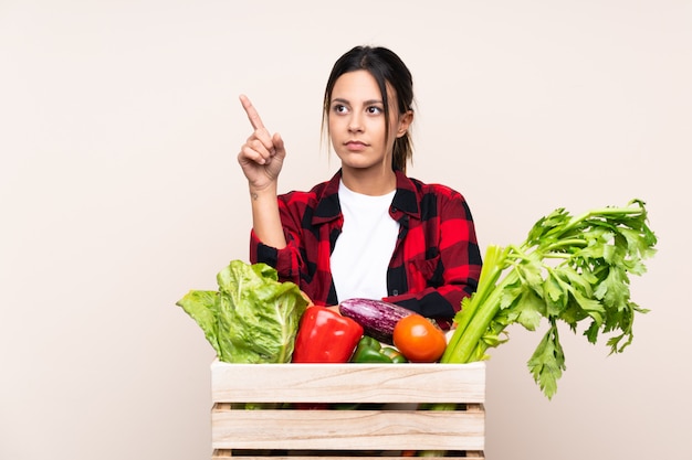 Mujer del granjero que sostiene verduras frescas en una cesta de madera que toca en la pantalla transparente