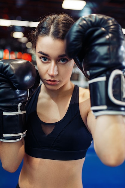 Foto mujer en guantes de boxeo negros en el ring, vista frontal de cerca, entrenamiento de caja.