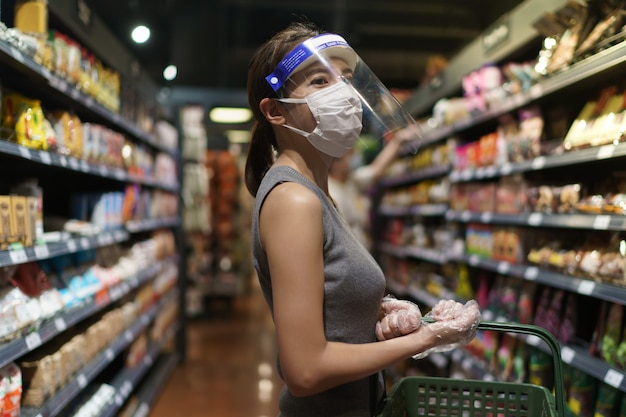 Mujer con guantes, careta y máscara. Compras de pánico durante la pandemia del virus corona.