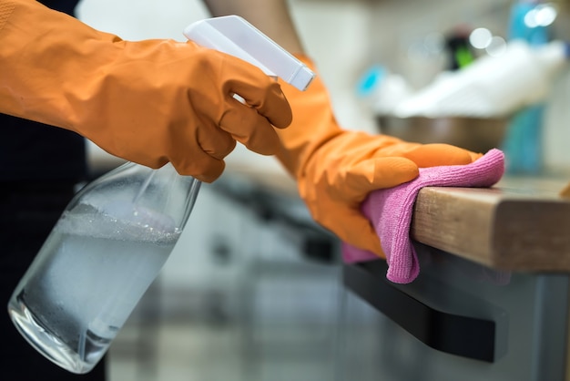 Mujer con guantes de goma limpiando la encimera de la cocina